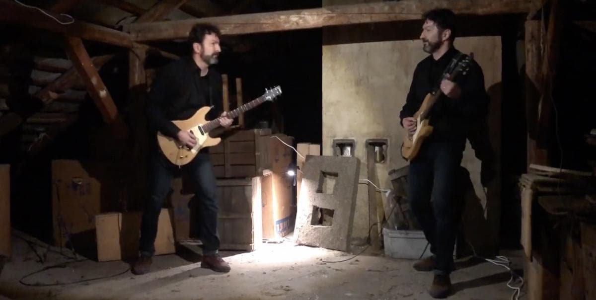 Duplicated Tamás Hajas play the guitar in an attic.
